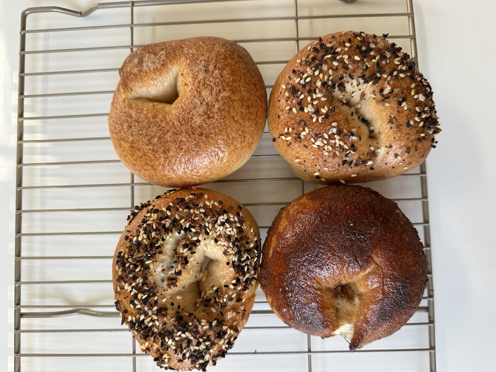 Bagels with a deeper golden crust cooling on a rack